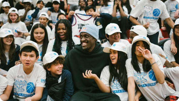 Pascal Siakam sitting with a group of kids.